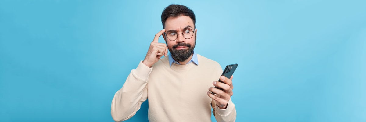 Cep Telefonu Reklam Virüsü Nasıl Temizlenir sorusunu düşünen mavi arkafonda yer alan düşünen elinde cep telefonu olan bir adam